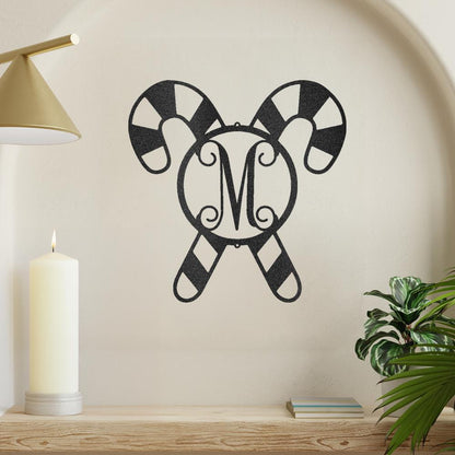 Black metal candy cane wall art with a striped pattern and a decorative "M" monogram in the center.