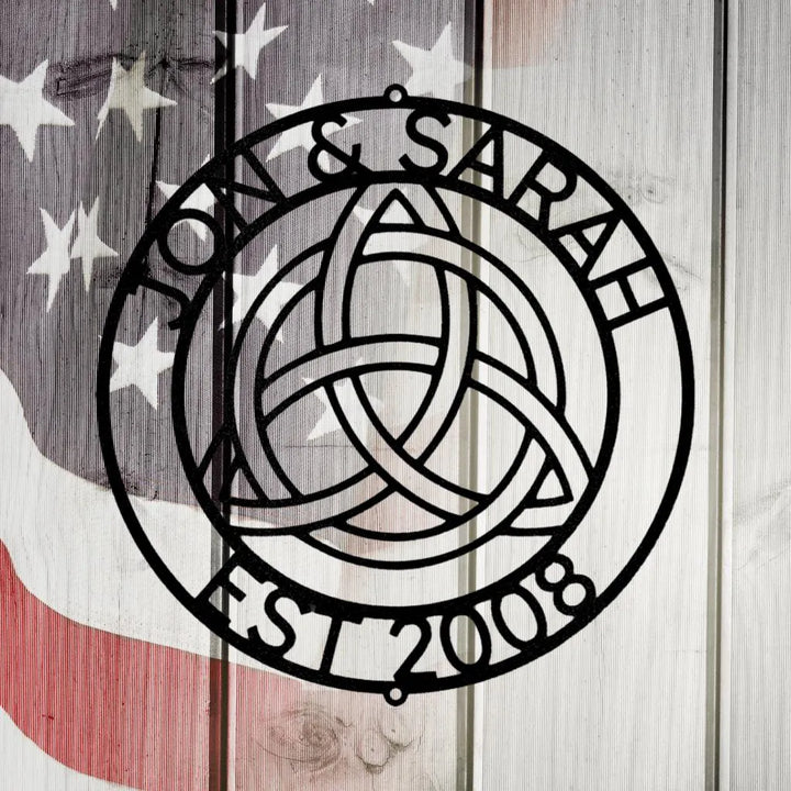 Black metal Celtic knot monogram wall art with "Jon & Sarah EST 2008" on a rustic American flag background.