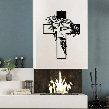 Black metal Christ Cross wall art with Jesus's face and crown of thorns, mounted above a modern fireplace.