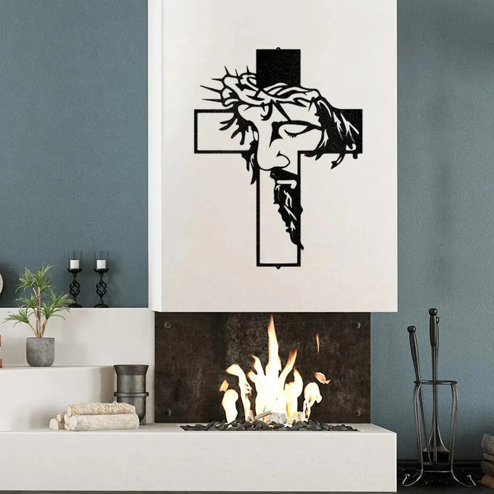 Black metal Christ Cross wall art with Jesus's face and crown of thorns, mounted above a modern fireplace.