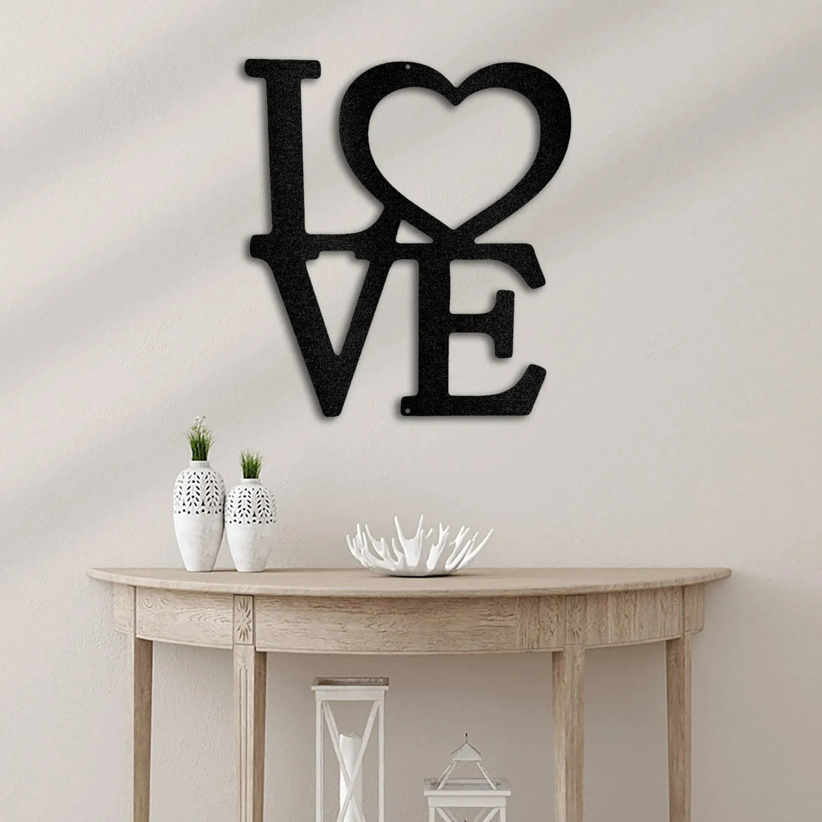 Black metal "LOVE" wall art with a heart replacing the "O" above a wooden console table.