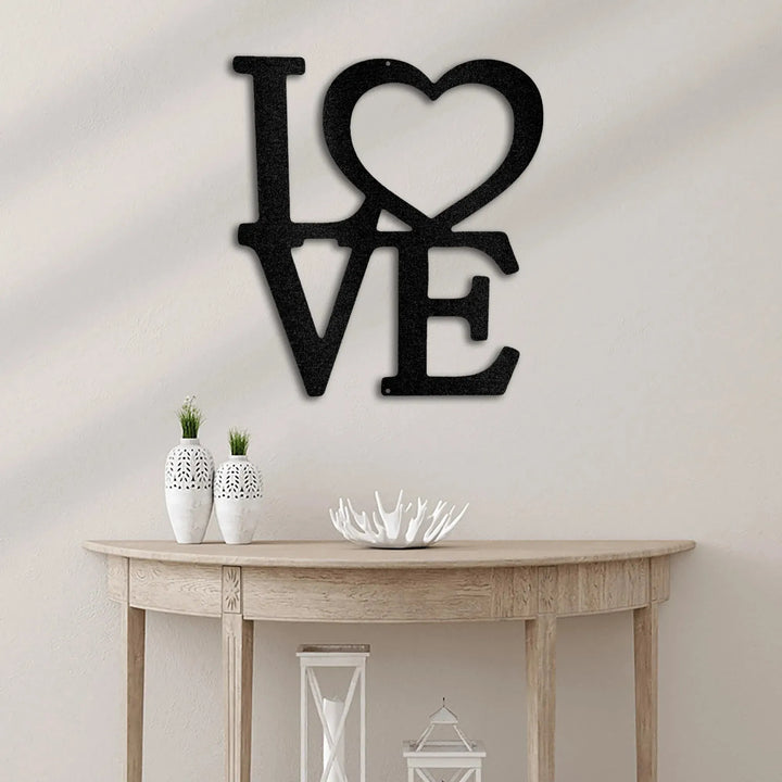 Black metal "LOVE" wall art with a heart replacing the "O" above a wooden console table.