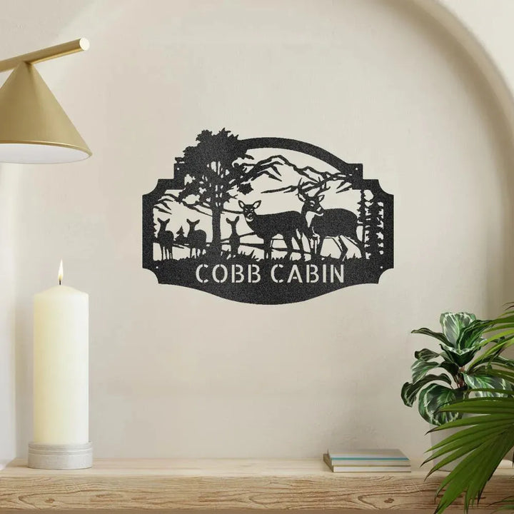 Black metal Deer Family Monogram wall art with "COBB CABIN" text, featuring deer, trees, and mountains.