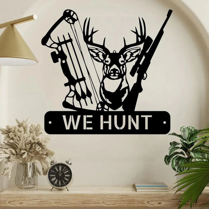 Black metal deer hunter monogram wall art featuring a deer head, bow, rifle, and "WE HUNT" text.