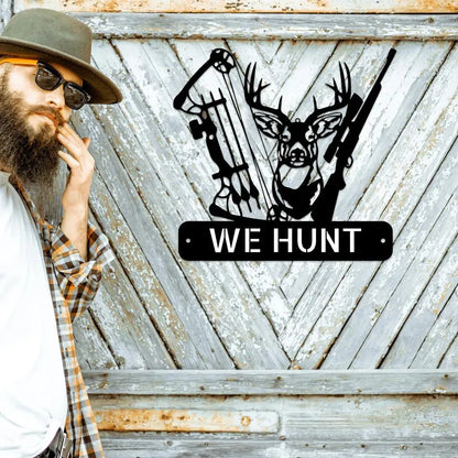 Black metal "WE HUNT" sign with deer head, bow, and rifle, mounted on a rustic wooden wall.