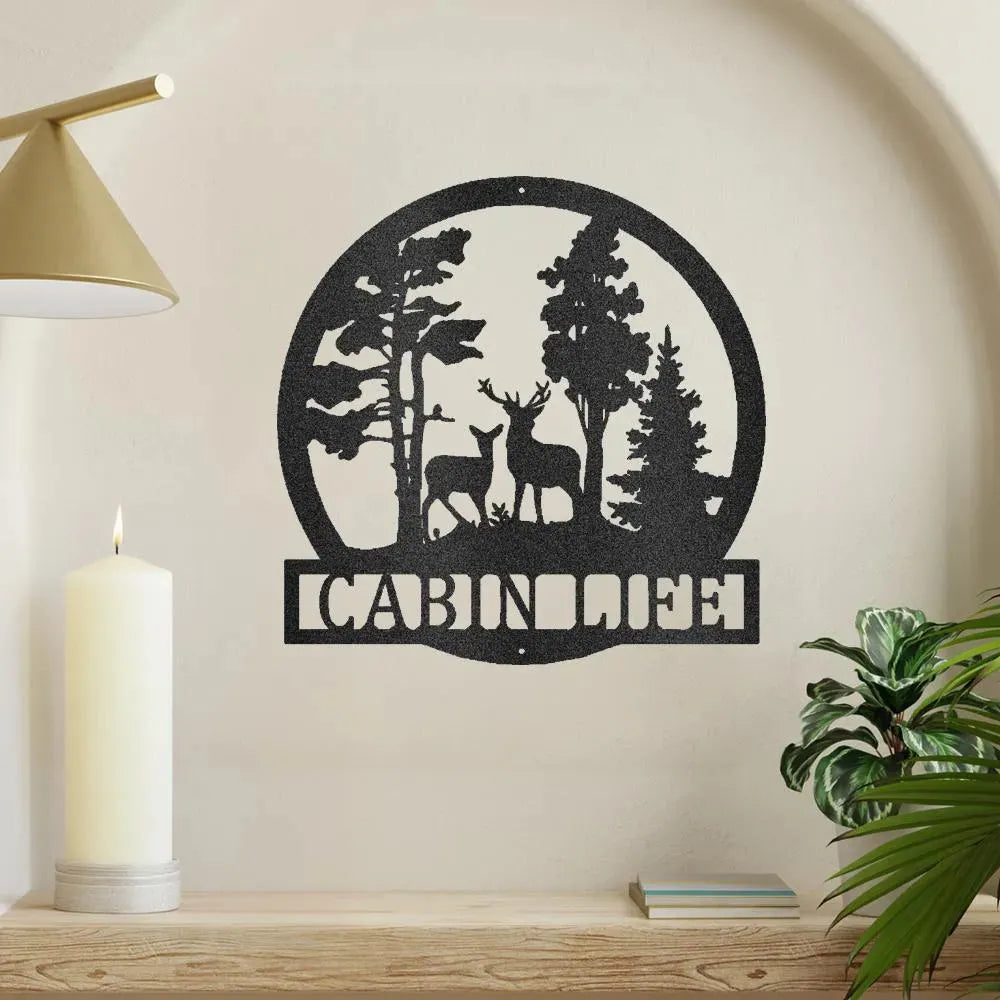 Black metal "Cabin Life" wall art with deer and pine trees in a circular design.