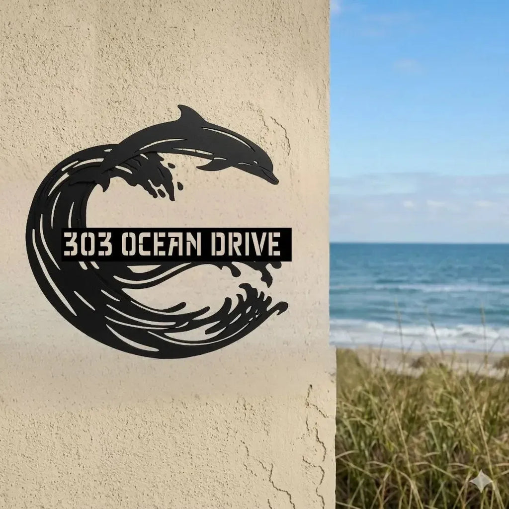 Decorative metal sign with dolphin design and '303 Ocean Drive' text on a textured wall, with a beach scene in the background.