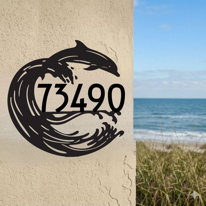 House number '73490' with a dolphin design on a textured wall, beach in the background.