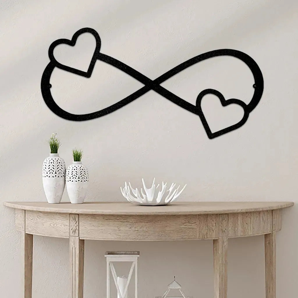 Black metal infinity symbol wall art with two hearts, one on each loop, mounted above a wooden console table.