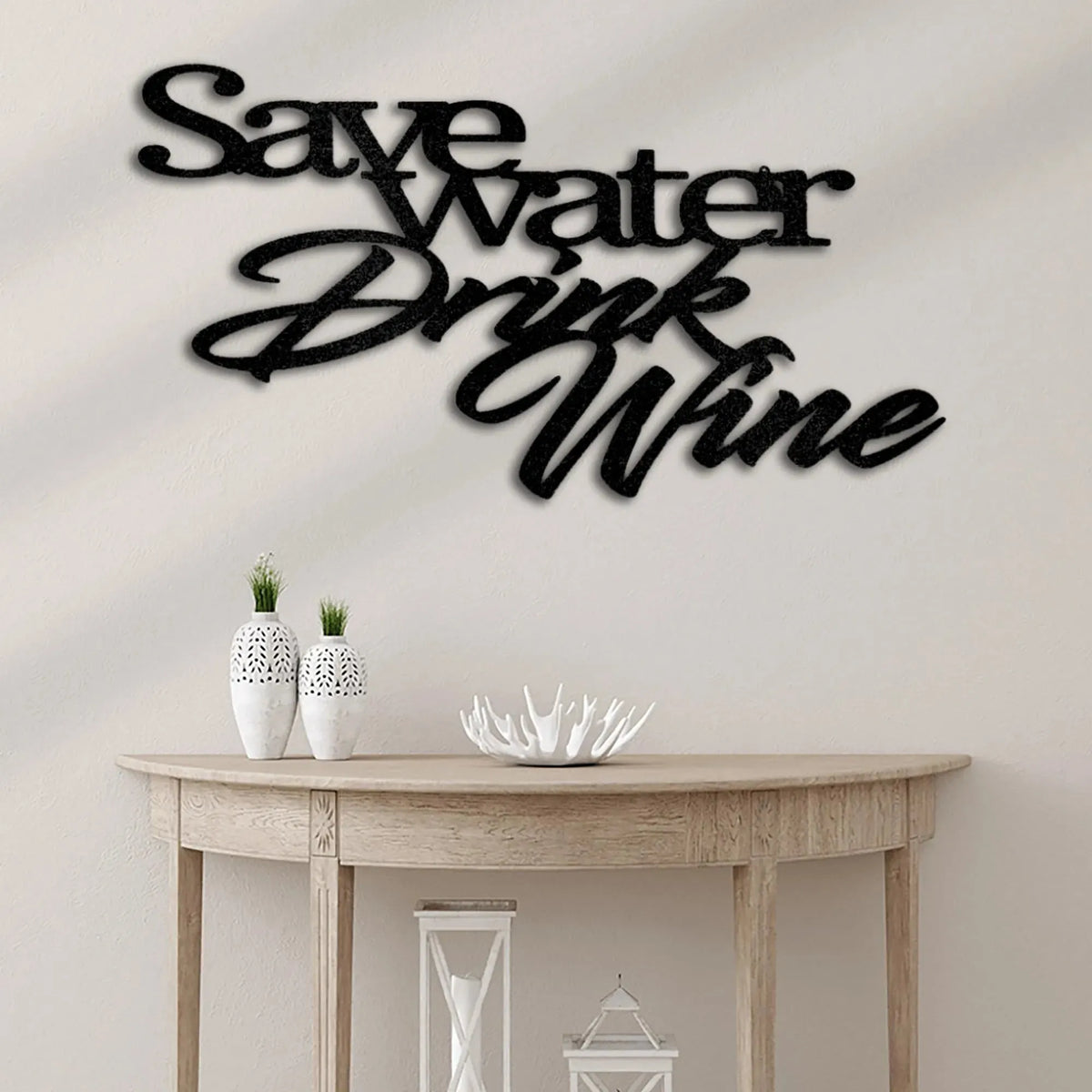 Black metal "Save Water Drink Wine" wall art above a light wood console table.
