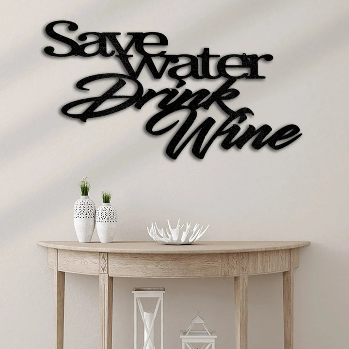 Black metal "Save Water Drink Wine" wall art above a light wood console table.