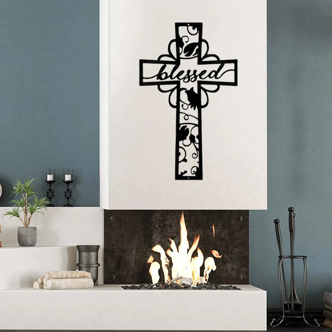 Black metal cross wall art with "blessed" cutout text and decorative scrollwork above a fireplace.