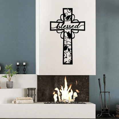 Black metal cross wall art with "blessed" cutout text and decorative scrollwork above a fireplace.