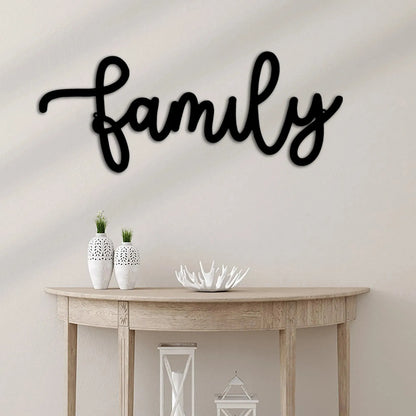 Black script "Family" metal wall art above a wooden console table with white vases.