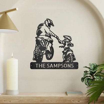 Black metal wall art of a father and son on motocross bikes, with "THE SAMPSONS" personalized text.
