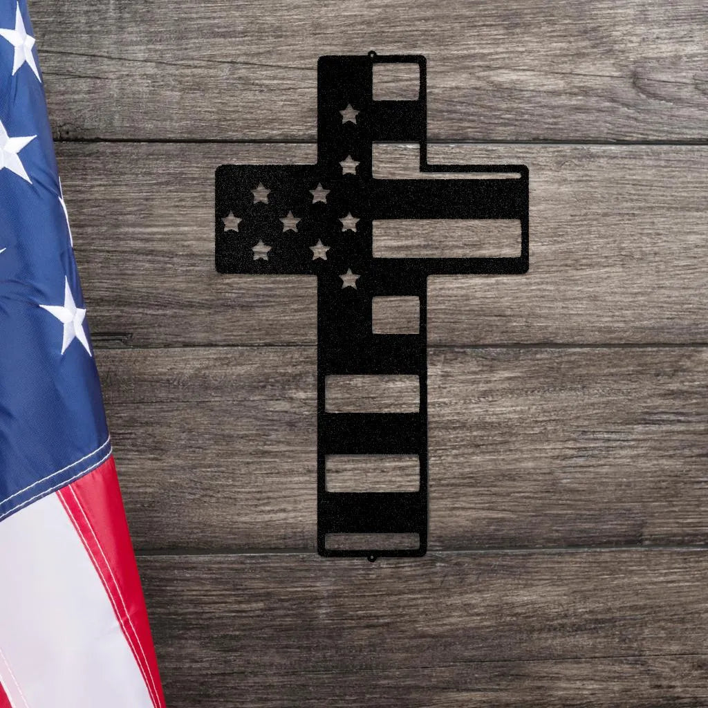 Black metal cross wall art with American flag design, stars, and stripes, on a wooden background.