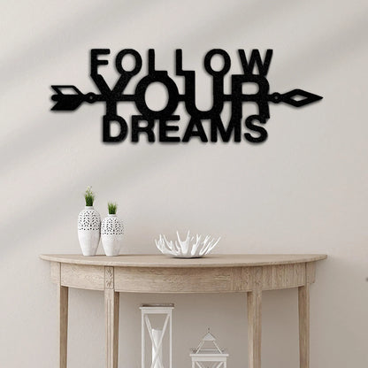 Black metal wall art spelling "FOLLOW YOUR DREAMS" with an arrow, above a wooden console table.
