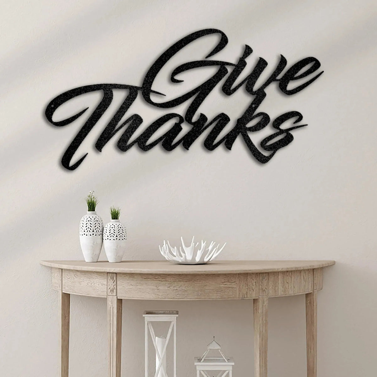 Black "Give Thanks" metal wall art in elegant script, mounted above a wooden console table.