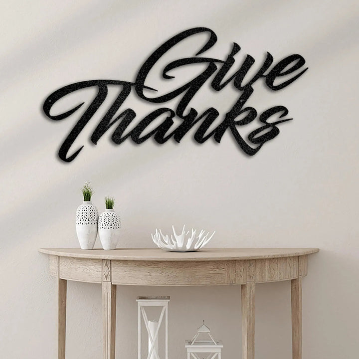 Black "Give Thanks" metal wall art in elegant script, mounted above a wooden console table.