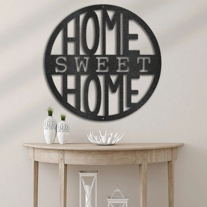 Black circular metal wall art with "HOME SWEET HOME" cutout, hanging above a wooden console table.