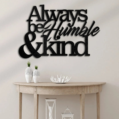 Black metal wall art decor with "Always be Humble & Kind" in mixed fonts, displayed above a wooden console table.