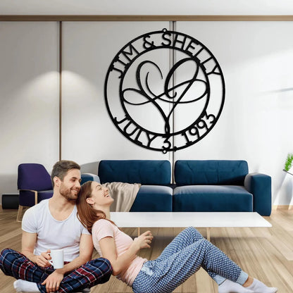 Black metal "Jim & Shelly July 3, 1993" monogram with intertwined heart, hanging in a modern living room.