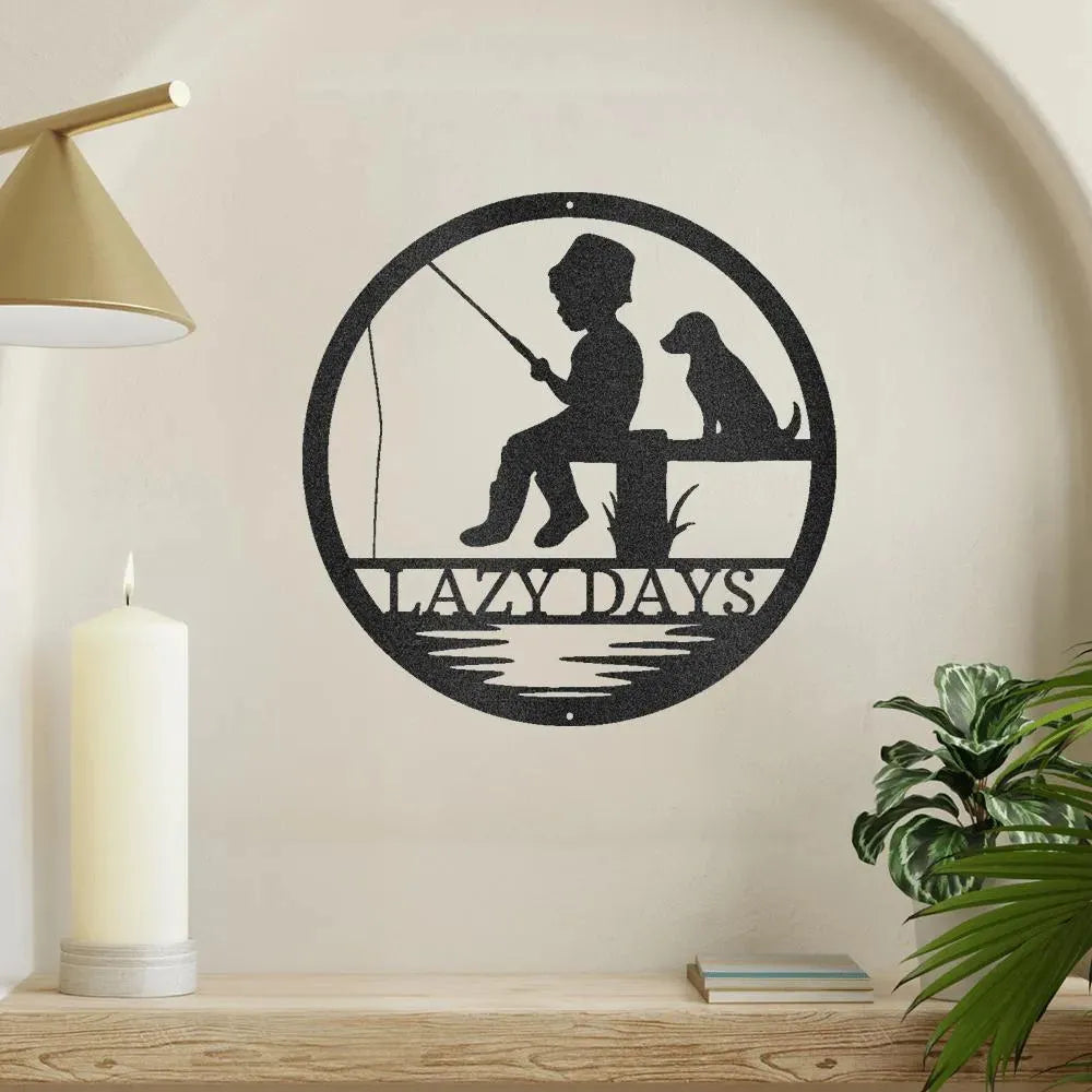 Black metal wall art: boy fishing with dog, "LAZY DAYS" text, circular design.