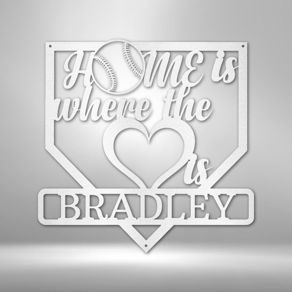 White metal baseball home plate sign with "HOME is where the heart is" and "BRADLEY" in script.