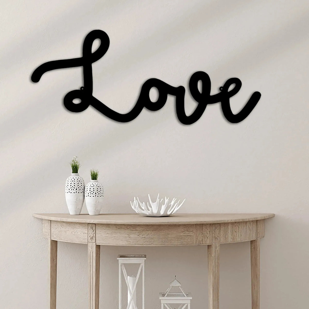 Black script "Love" metal wall art, powder-coated American steel, above a light wood console table.