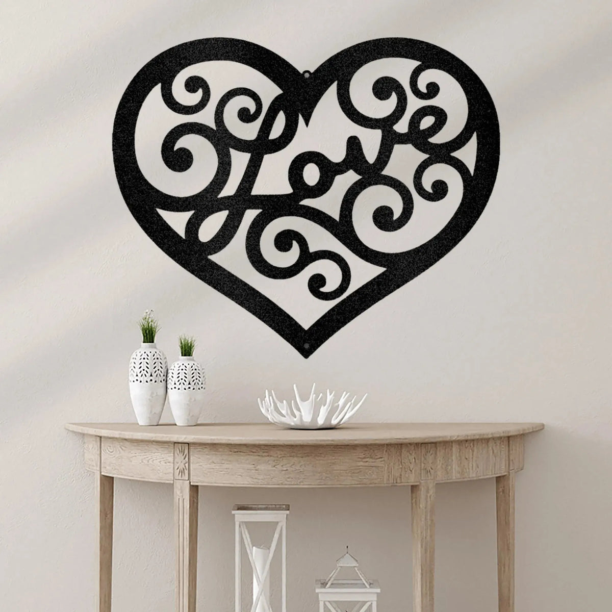 Black metal heart wall art with "Love" in a decorative swirl script, hanging above a wooden console table.