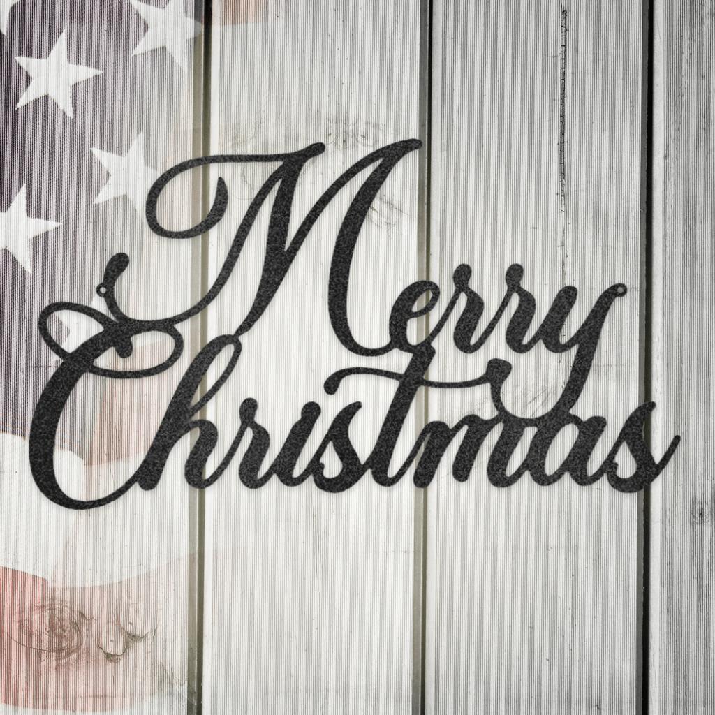 Black script metal "Merry Christmas" wall art on a rustic white wooden background with a subtle American flag.
