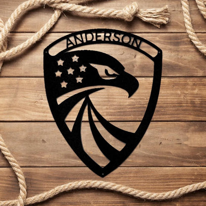 Black metal American eagle shield monogram with "ANDERSON" and stars, on wood.
