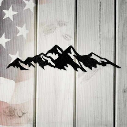 Black powder-coated American steel mountain range metal wall art on a rustic white wooden background.
