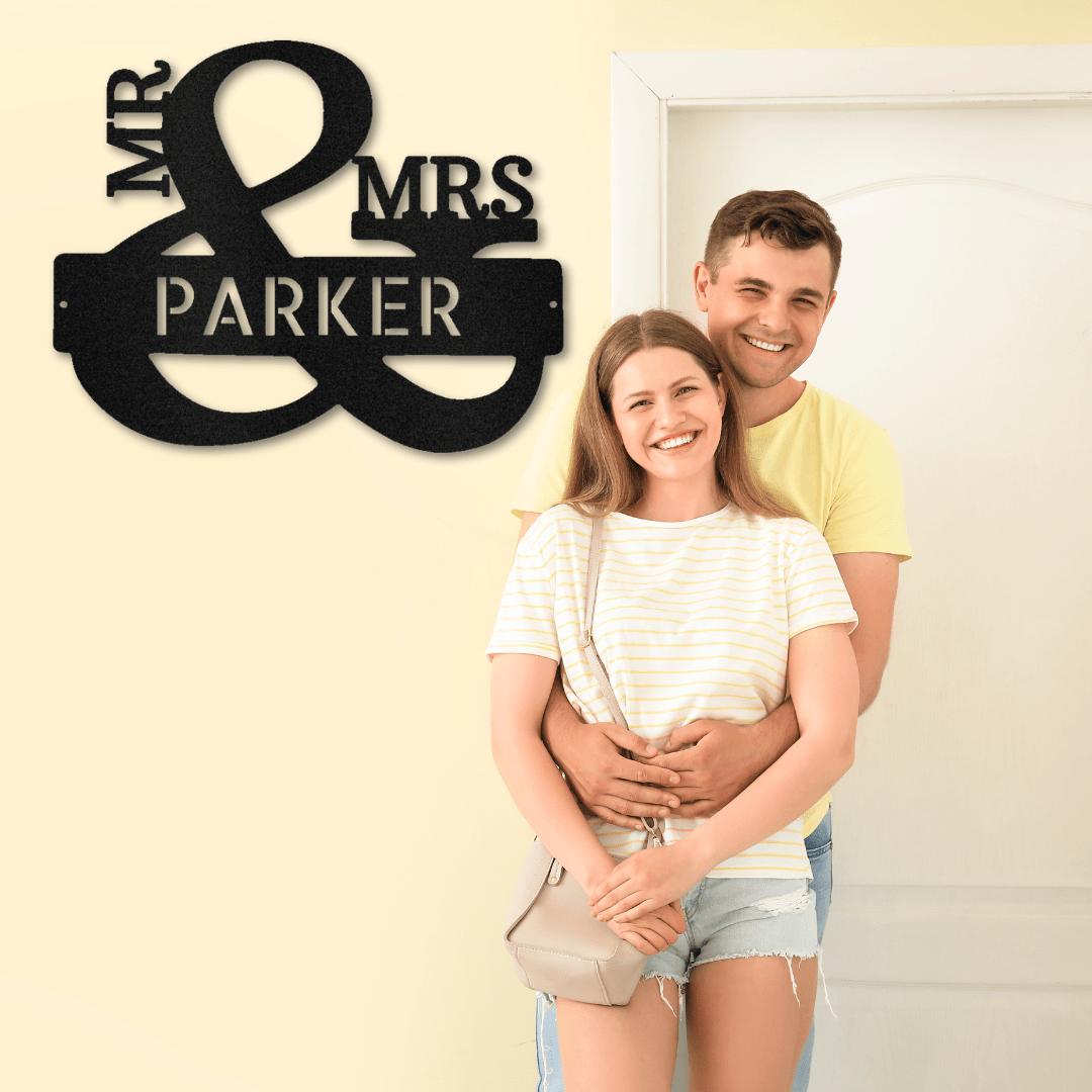 Black metal "Mr. & Mrs. Parker" personalized wall art with a couple smiling in the background.