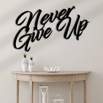 Black "Never Give Up" metal wall art in a script font, displayed above a light wood console table.