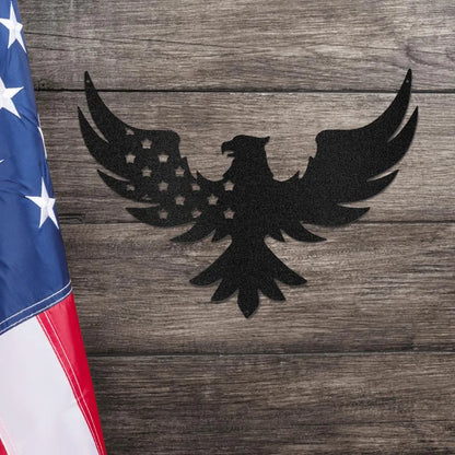 Black metal eagle wall art with stars on its wing, next to an American flag on a wooden background.