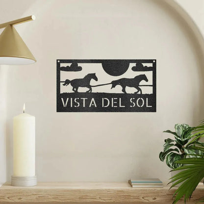 Black metal racing horses monogram sign with "VISTA DEL SOL" text, sun, and clouds.