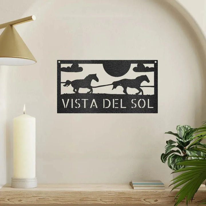 Black metal racing horses monogram sign with "VISTA DEL SOL" text, sun, and clouds.