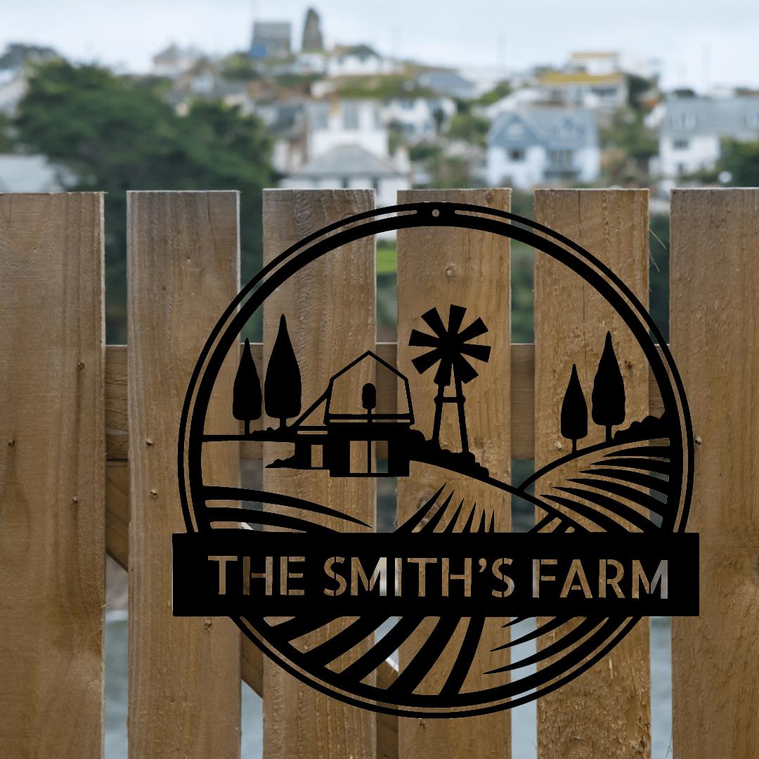 Black metal farm monogram sign with windmill, barn, trees, and "THE SMITH'S FARM" text on a wooden fence.