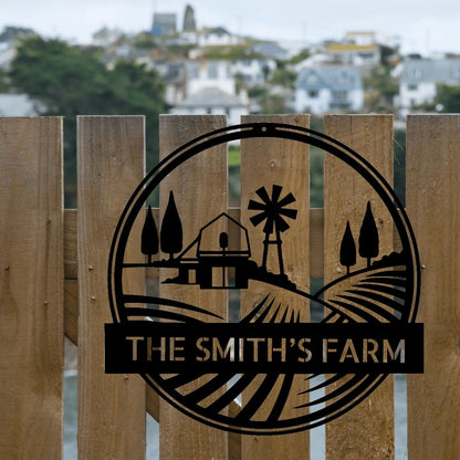 Black metal farm monogram sign with windmill, barn, trees, and "THE SMITH'S FARM" text on a wooden fence.