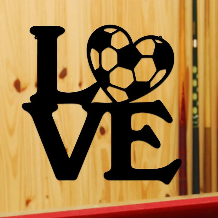 Black metal "LOVE" wall art with a soccer ball heart, on a light wood background.