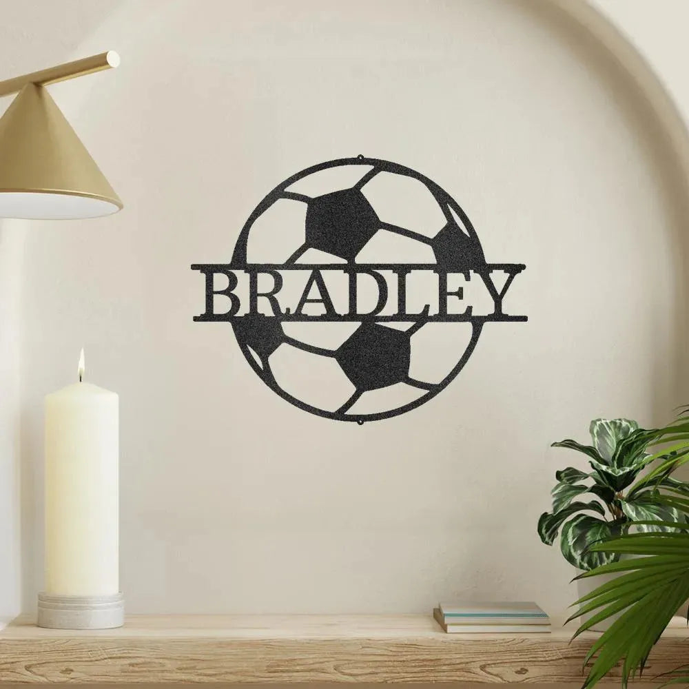Black metal soccer ball monogram wall art with "BRADLEY" cut out, mounted on a light wall.