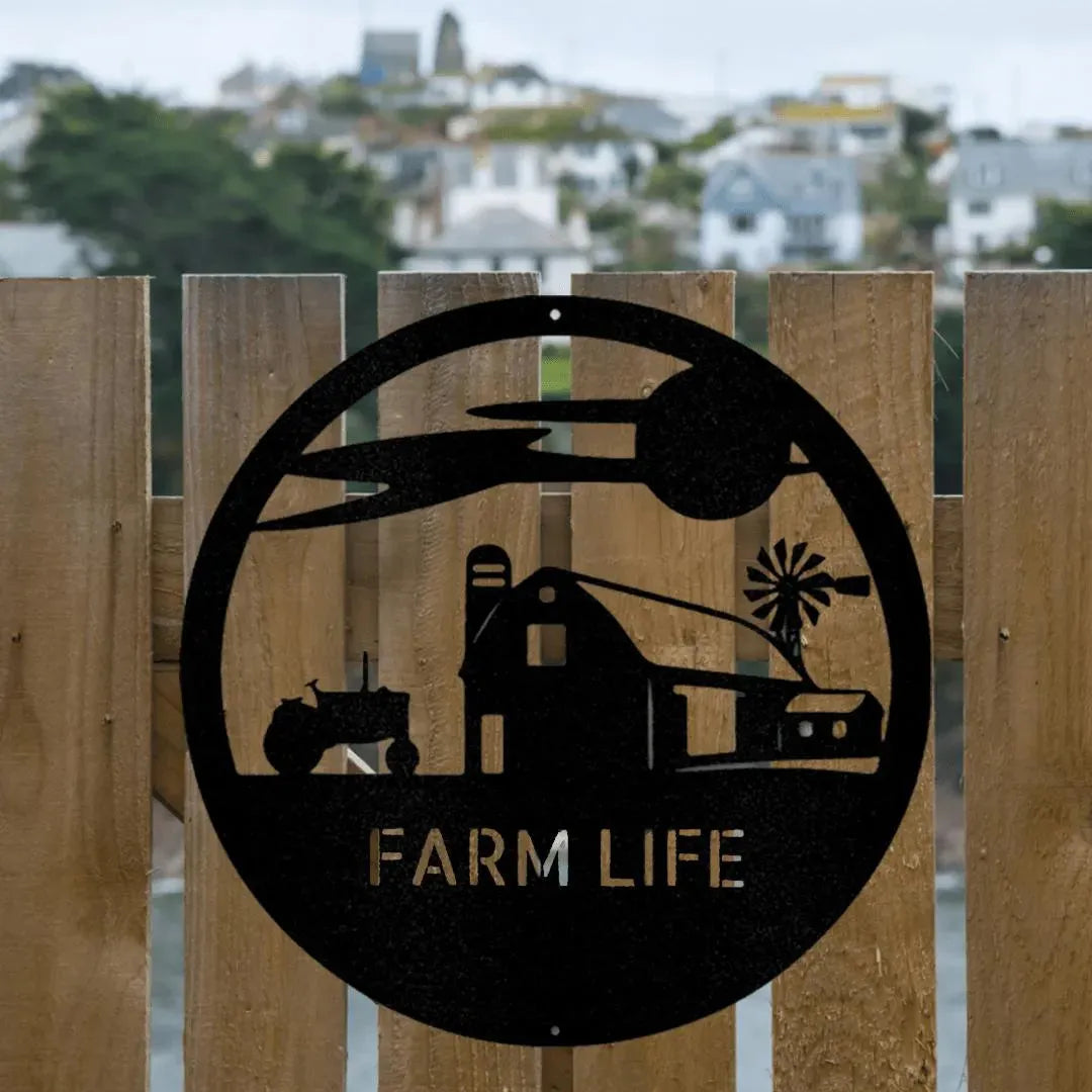 Black metal "Farm Life" monogram art featuring a barn, tractor, silo, and windmill, mounted on a wooden fence.