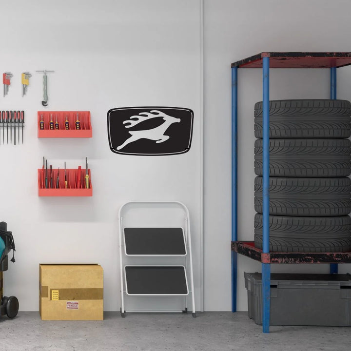 Garage interior with shelves, tools, and Triumph Stag sign against a white wall.