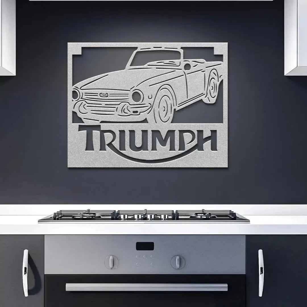 Metal wall art of a Triumph car on a dark wall above a kitchen stove.