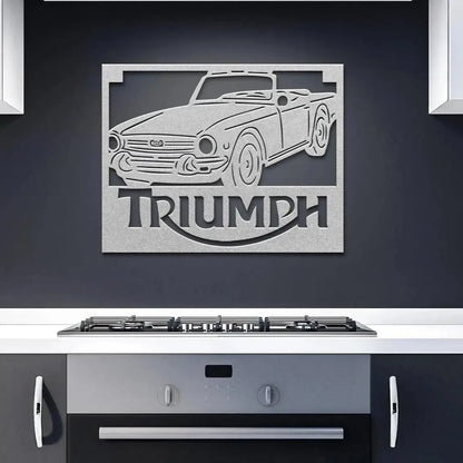 Metal wall art of a Triumph car on a dark wall above a kitchen stove.