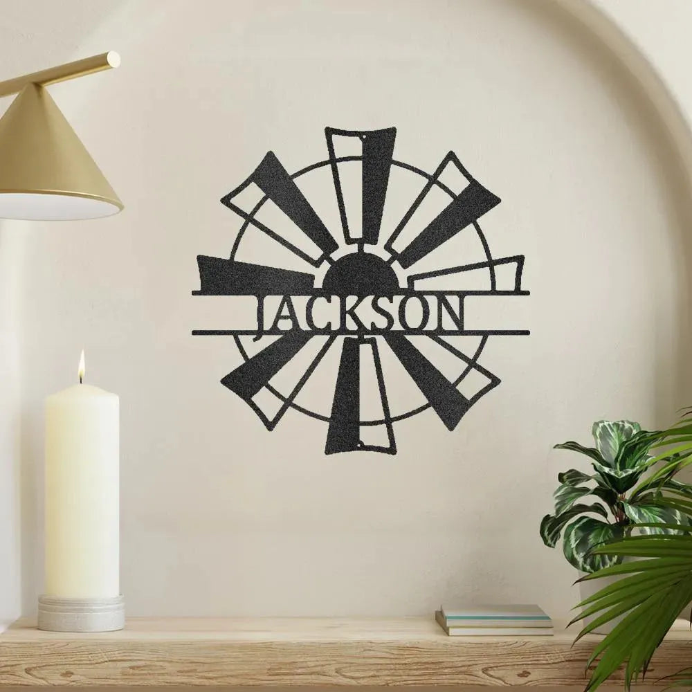 Black metal windmill monogram wall art with "JACKSON" cut out, displayed on a light wall.