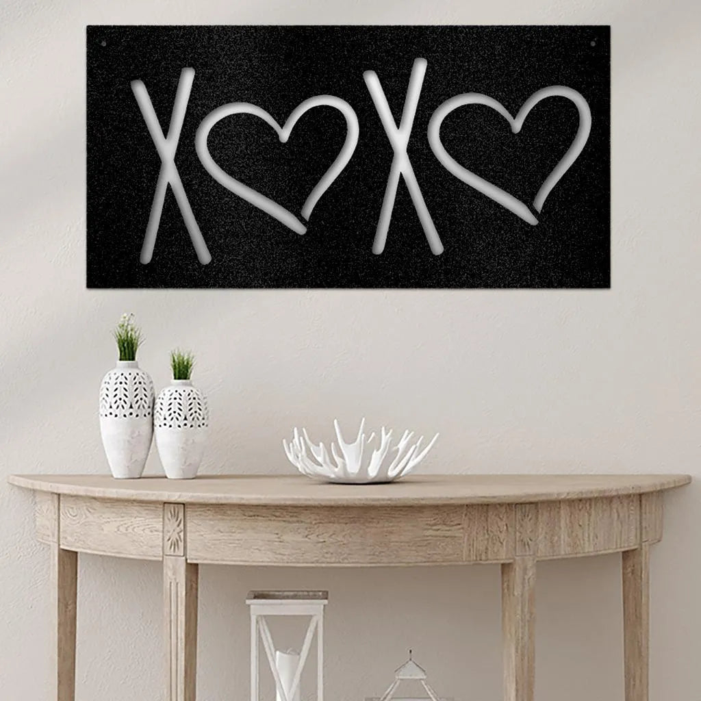 Black metal XOXO wall art with white letters and hearts, displayed above a wooden console table.