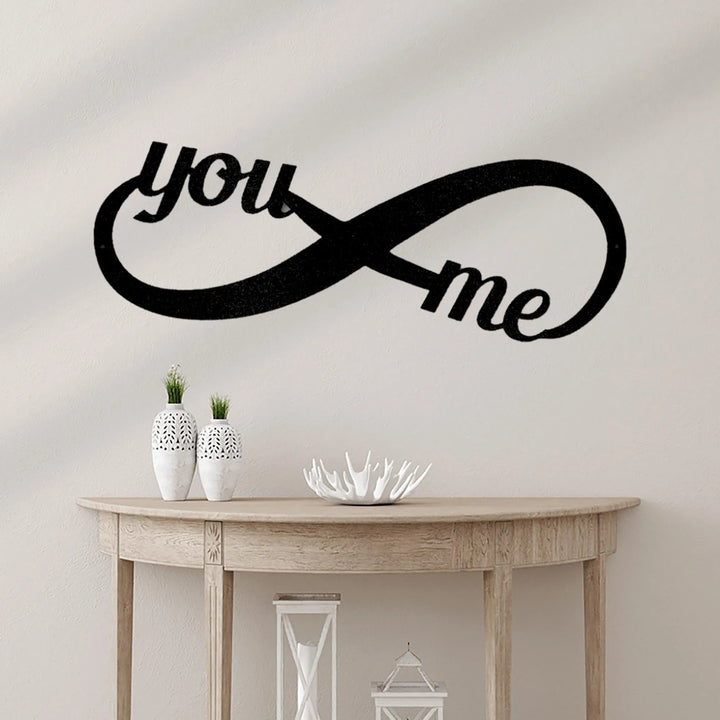 Black metal "You & Me" infinity symbol wall art above a light wood console table.